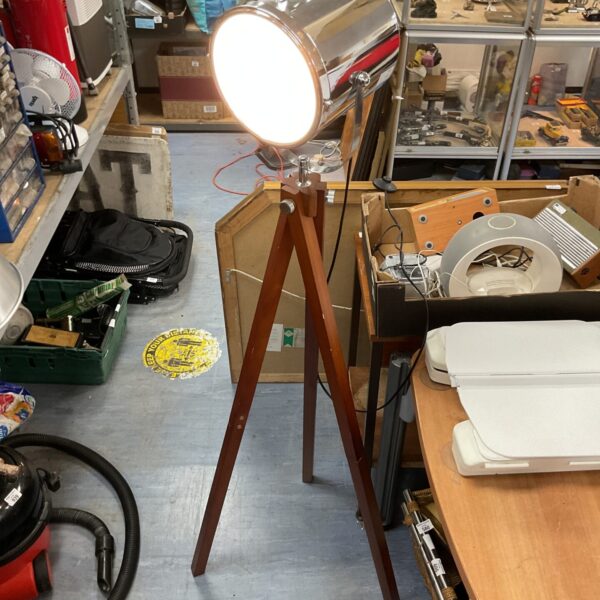 Vintage floor spotlight on wooden tripod base.