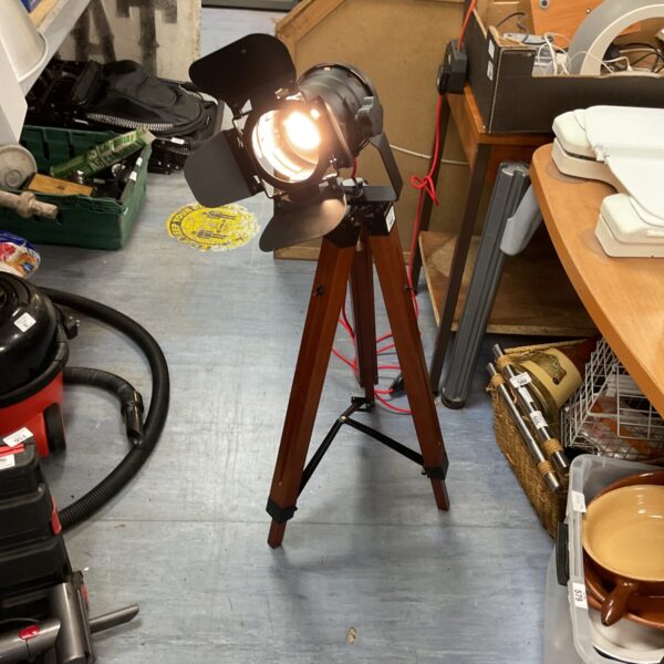Vintage spotlight on wooden tripod, studio lighting equipment.