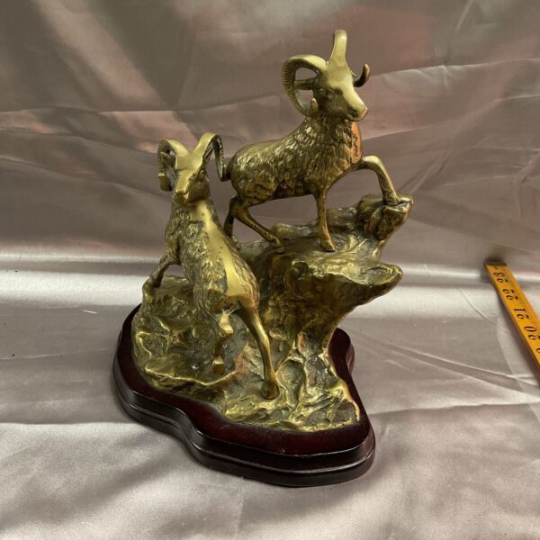 Vintage brass mountain goat sculpture on wooden base.