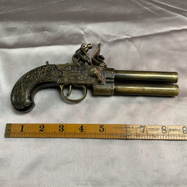 Detailed brass double barrel flintlock pistol reproduction for collectors.