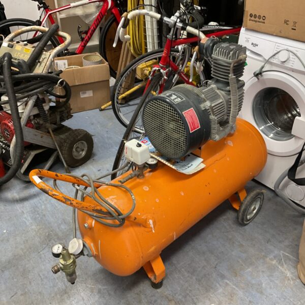 Orange Kaeser 100L air compressor in a cluttered workshop.