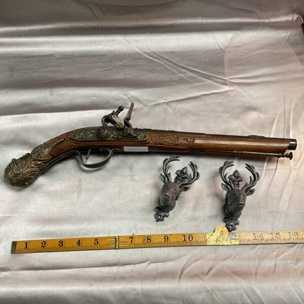 Detailed reproduction flintlock pistol with wall brackets for display.