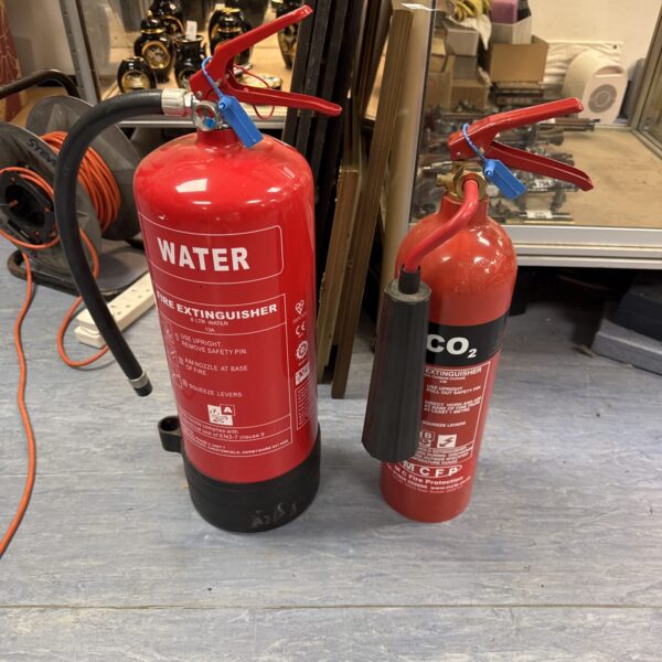 Two vintage red fire extinguishers for collectors and display.