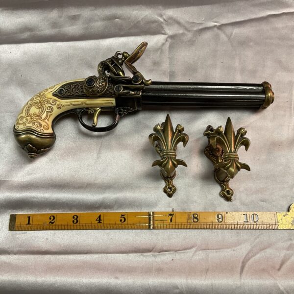 Decorative reproduction Italian flintlock pistol with wall brackets for display.