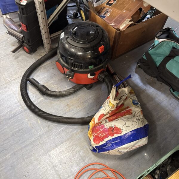 Red Numatic Henry hoover with pole attachment for cleaning.
