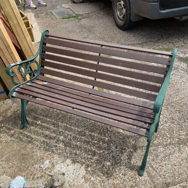 Vintage garden bench with decorative cast iron ends in a garden setting.