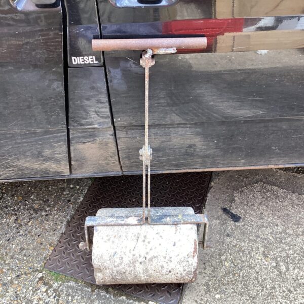 Vintage metal garden roller for lawn compaction and maintenance.