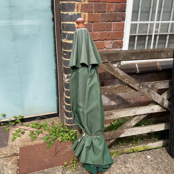 Green vintage garden parasol in a garden setting.