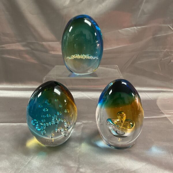 Three matching blue and gold glass paperweights for desk decor.