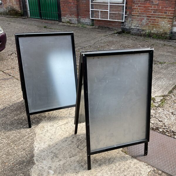 Two black metal advertising A boards on pavement.