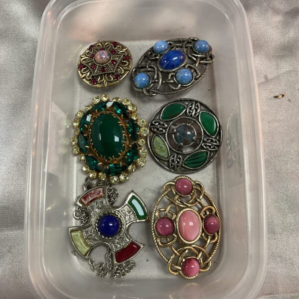 Vintage brooch lot featuring enamel and metal designs.