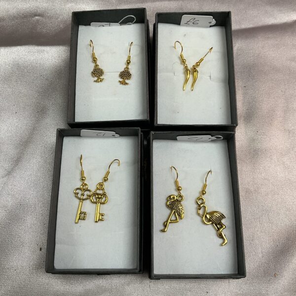 Four pairs of vintage silver gilt earrings displayed on a black background.