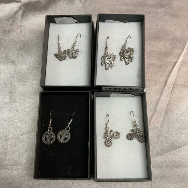 Close-up of four pairs of silver earrings with floral and leaf designs.