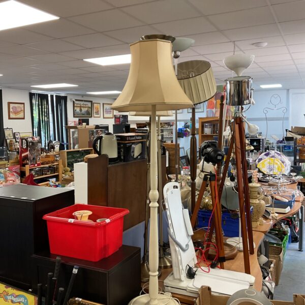 Vintage white standard lamp with cream shade in a room.