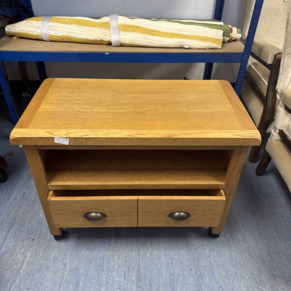 Light oak TV stand with single drawer and wheels for easy movement.