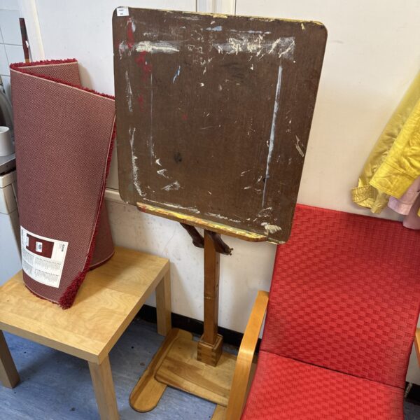 Vintage wooden artist easel with tilting surface in a studio setting.