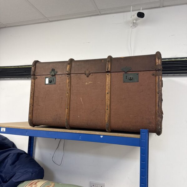 Large vintage steamer trunk with metal banding and a domed lid.