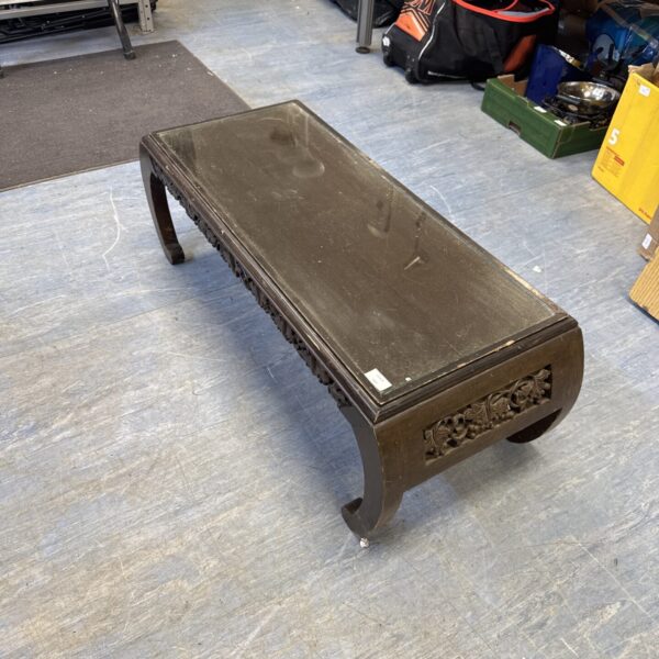Front view of vintage carved coffee table with glass top.