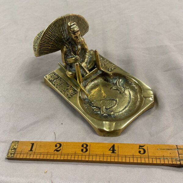 Vintage brass fisherman ashtray with detailed oriental figurine.