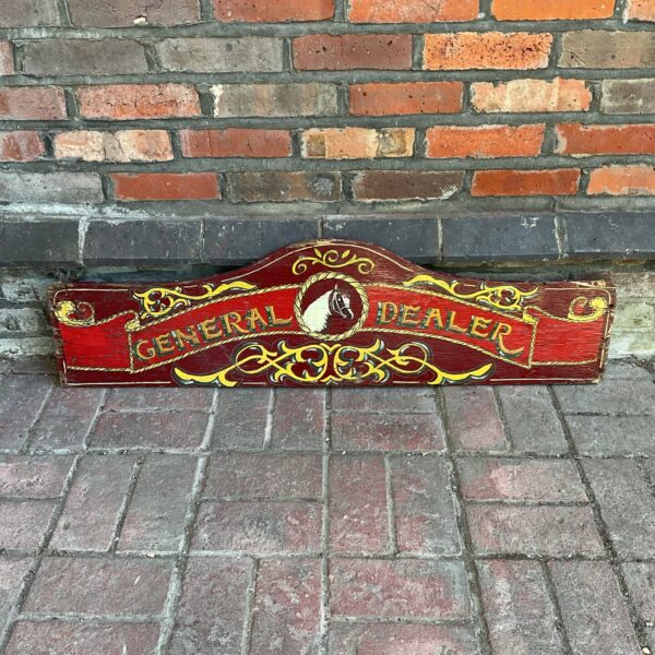 Vintage general dealer sign displayed against a brick wall.