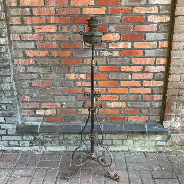 Vintage Globe Vulcan oil lamp on ornate wrought iron stand.