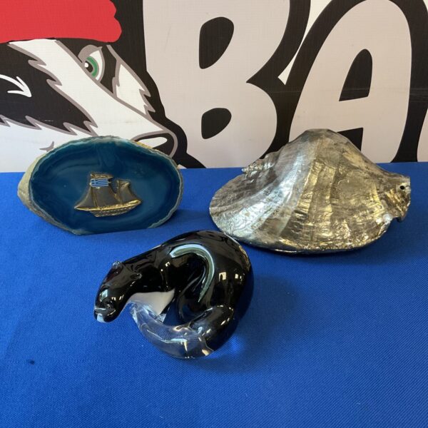 Glass paperweight collection featuring otter, conch shell and ship.