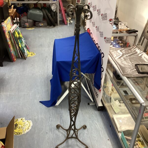 Ornate wrought iron lamp stand awaiting restoration.