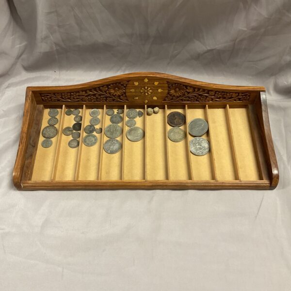 Vintage carved wood coin tray filled with coins.