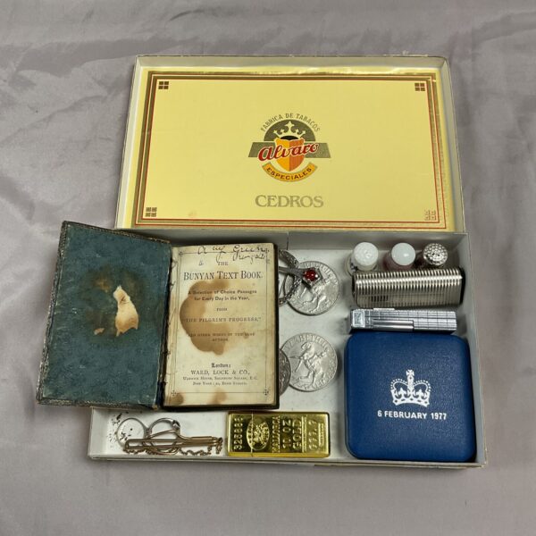 Vintage cigar box filled with lighters, thimbles, and a miniature book.