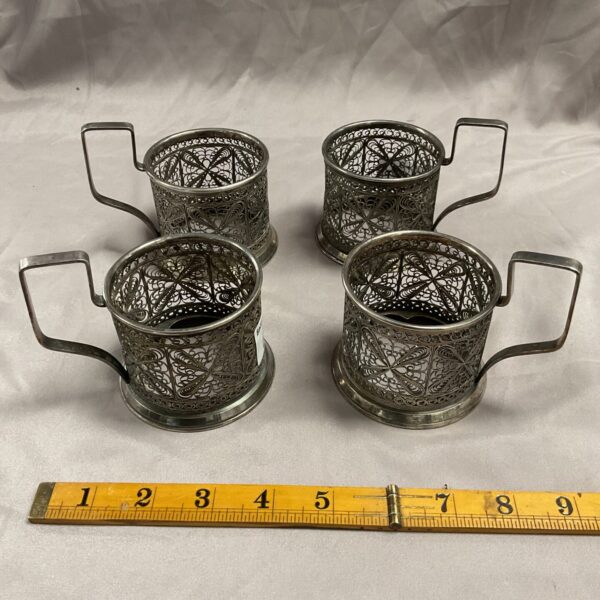 Set of four antique Russian filigree cup holders with ornate designs.