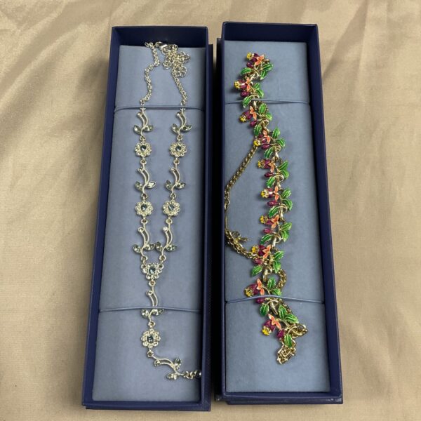 Two vintage costume jewellery necklaces with floral designs on a blue background.