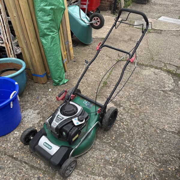Green Qualcast XSZ48B-SD petrol lawnmower in a garden setting.