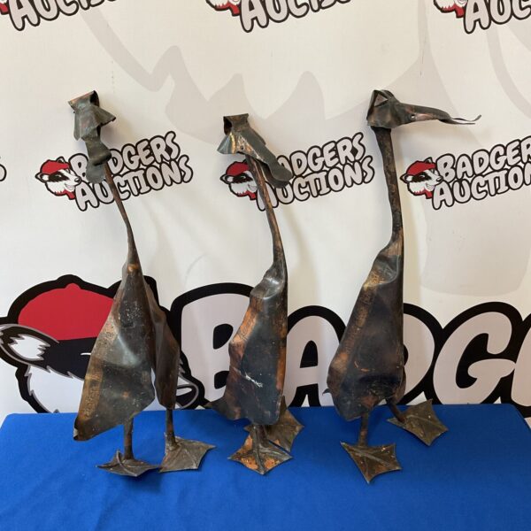 Three vintage copper ducks, rustic farmyard decor.