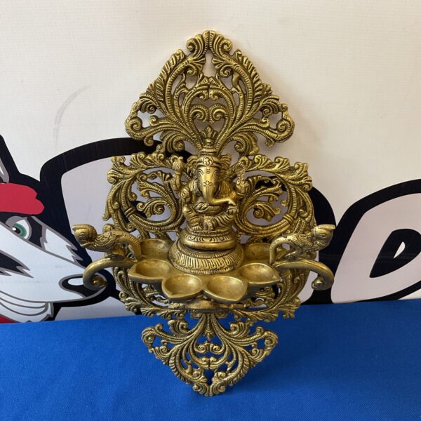 Intricate brass Vishnu wall sconce with detailed carving.