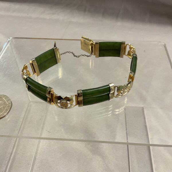 Antique Chinese jade bracelet with yellow metal setting.