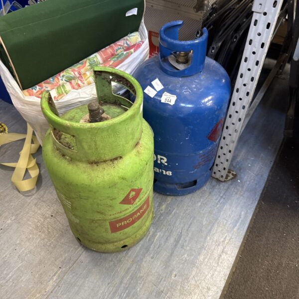 Pair of empty blue patio gas bottles for outdoor use.