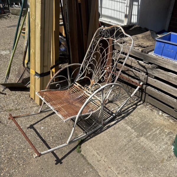 Vintage metal garden rocking chair with decorative detailing.