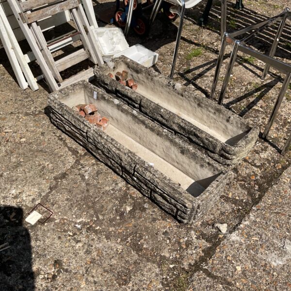 Pair of weathered concrete garden planters for outdoor use.