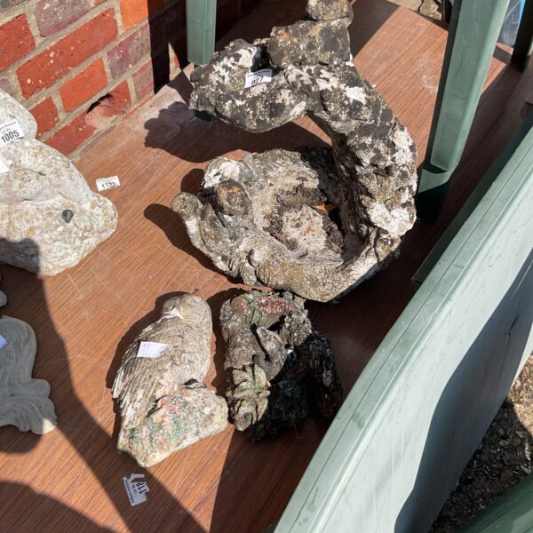 Weathered stone garden ornaments including an owl statue.