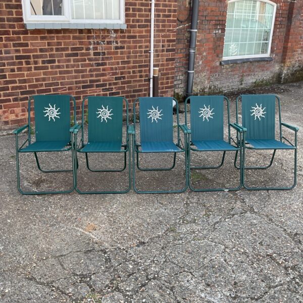 Five vintage green garden sun chairs in a garden setting.