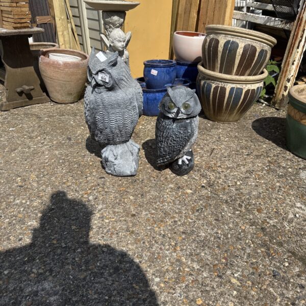 Pair of weighted plastic garden owl ornaments in a garden setting.