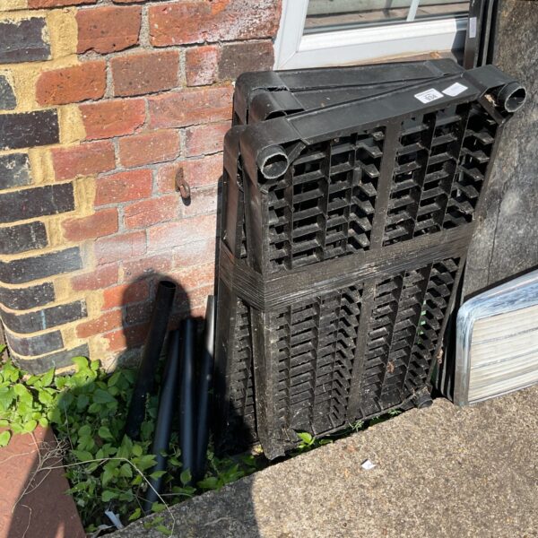 Black plastic storage racking sections in a garden setting.