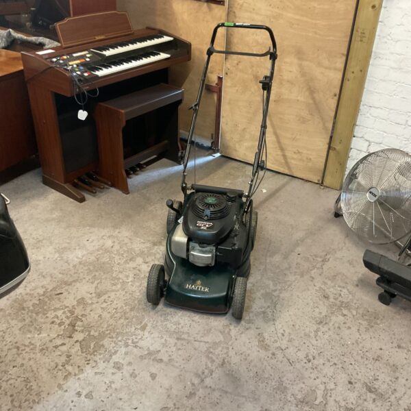 Hayter petrol mower with Honda GCV 135 engine in a garden setting.