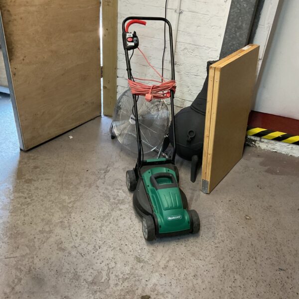 Vintage Qualcast electric mower in a garden setting.