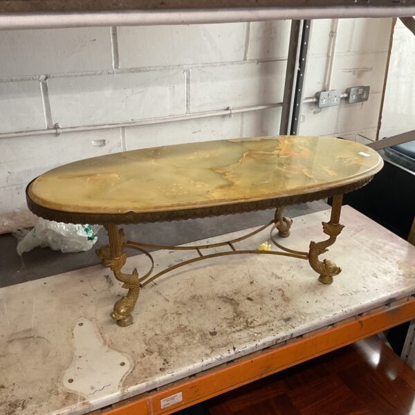 Vintage alabaster coffee table with brass legs in a storage area.