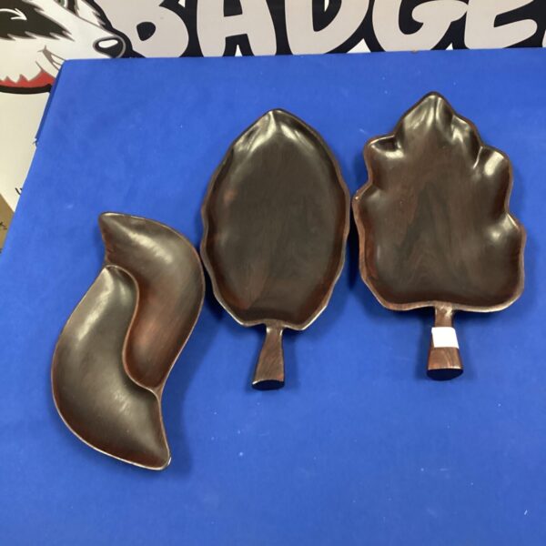 Three dark wood leaf bowls displayed on a surface.