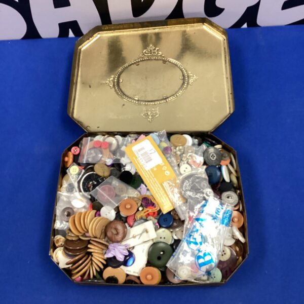 Vintage tin filled with a diverse button collection for crafting.