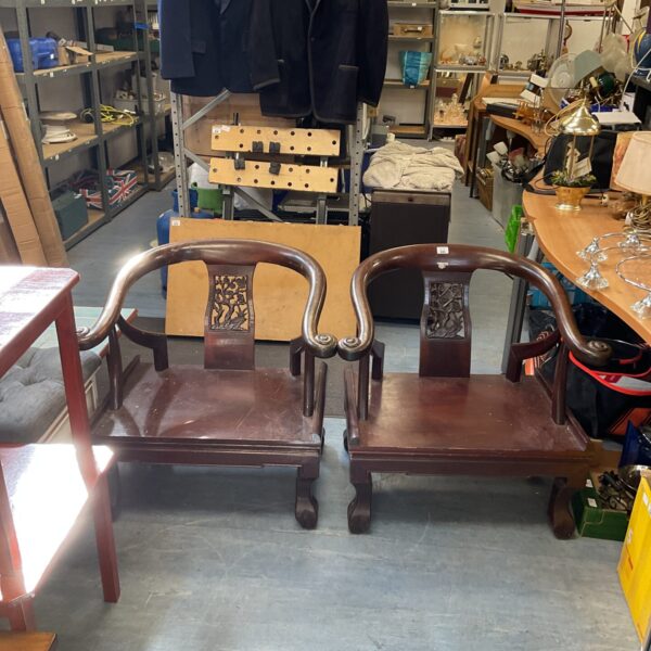 Pair of vintage Chinese carved hardwood chairs with floral details.