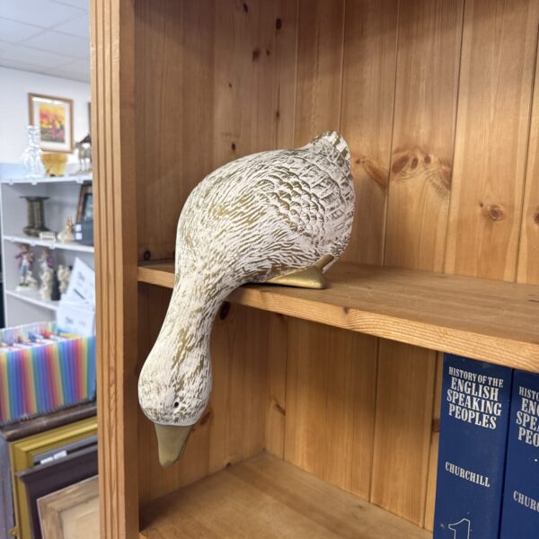 Vintage porcelain duck figurine displayed on a shelf.