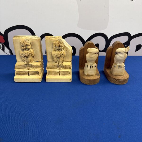 Vintage soapstone bookends with carved figures on a dark surface.